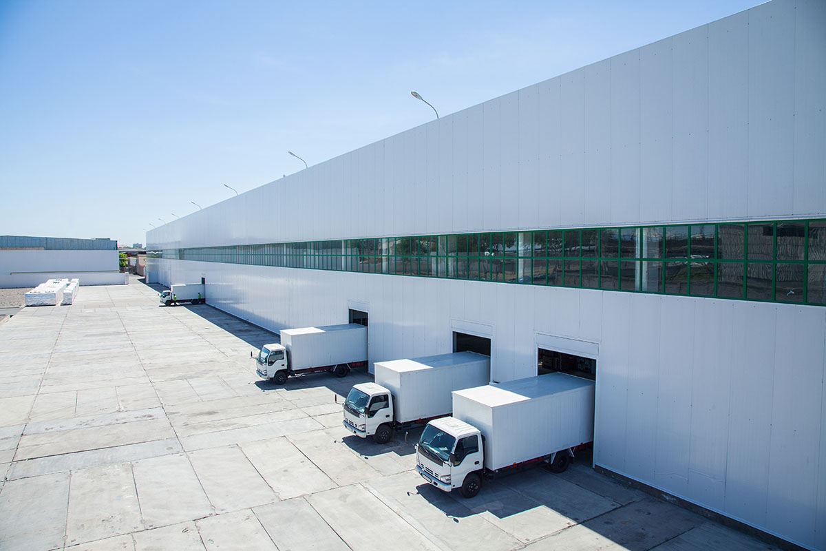 Facade of an industrial building and warehouse with freight cars in length