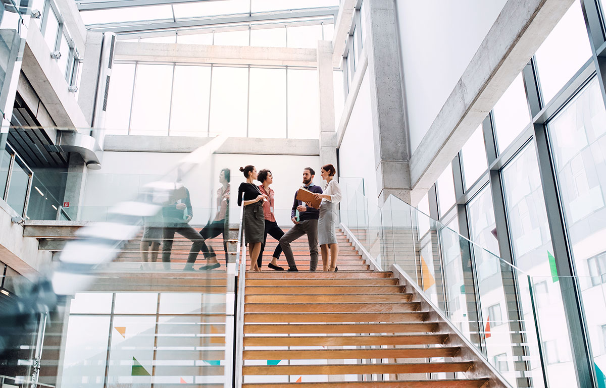 Group of young businesspeople standing on a staircase, talking