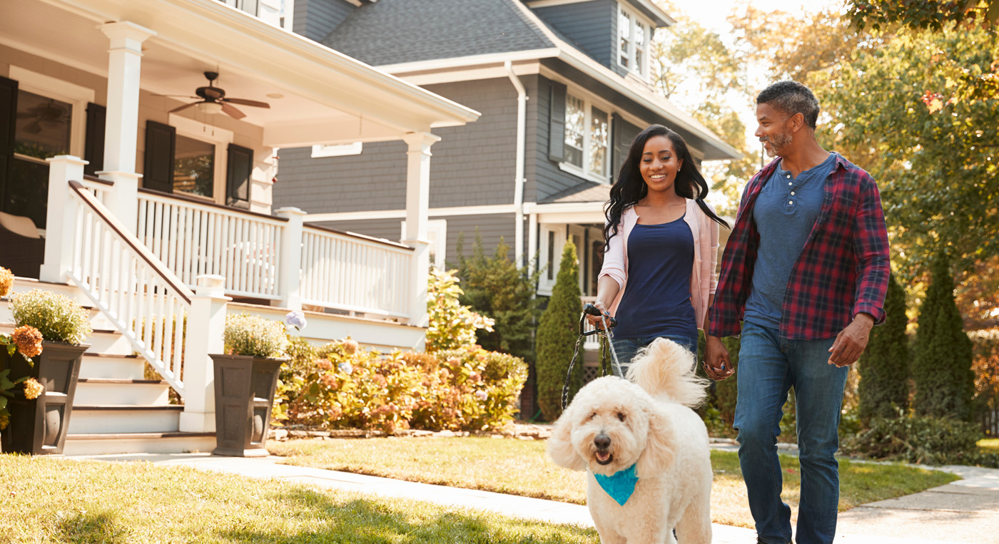 Millennial couple walking a dog through their neighborhood