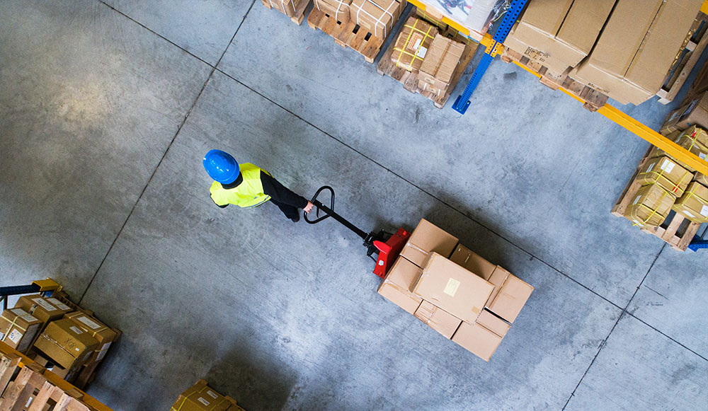 Male warehouse worker pulling a pallet truck.