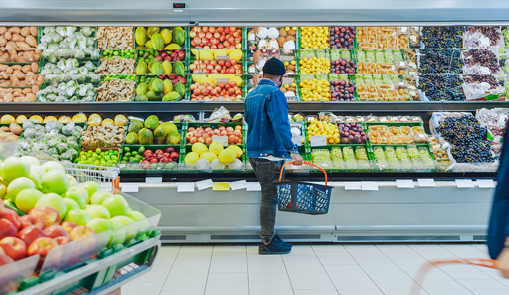 Man with Shopping Basket Shopping for Organic Fruits and Vegetables in the Fresh Produce Section of the Store