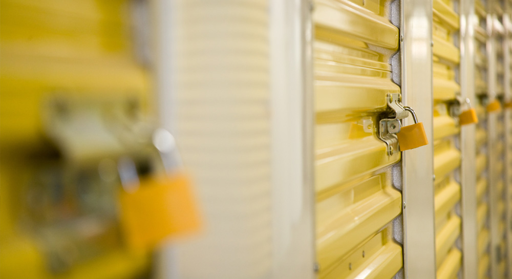Row of self-storage unit doors locked with padlocks in a public storage facility
