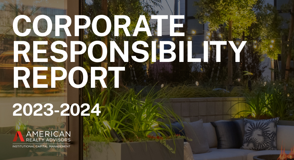 Look out on to an outdoor patio space with plants, trees, and a couch beside a fire pit