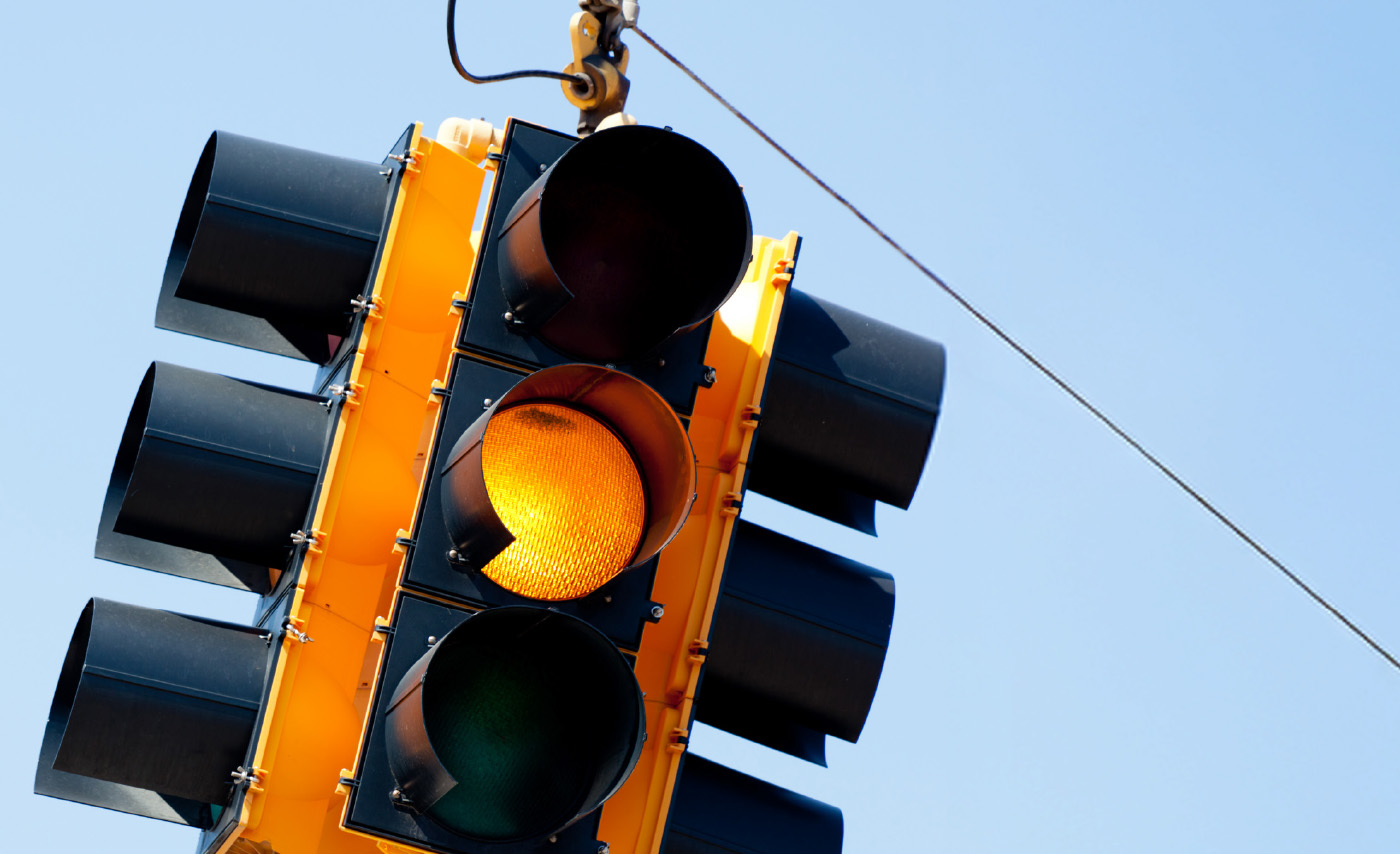 A yellow stop light set against a blue sky