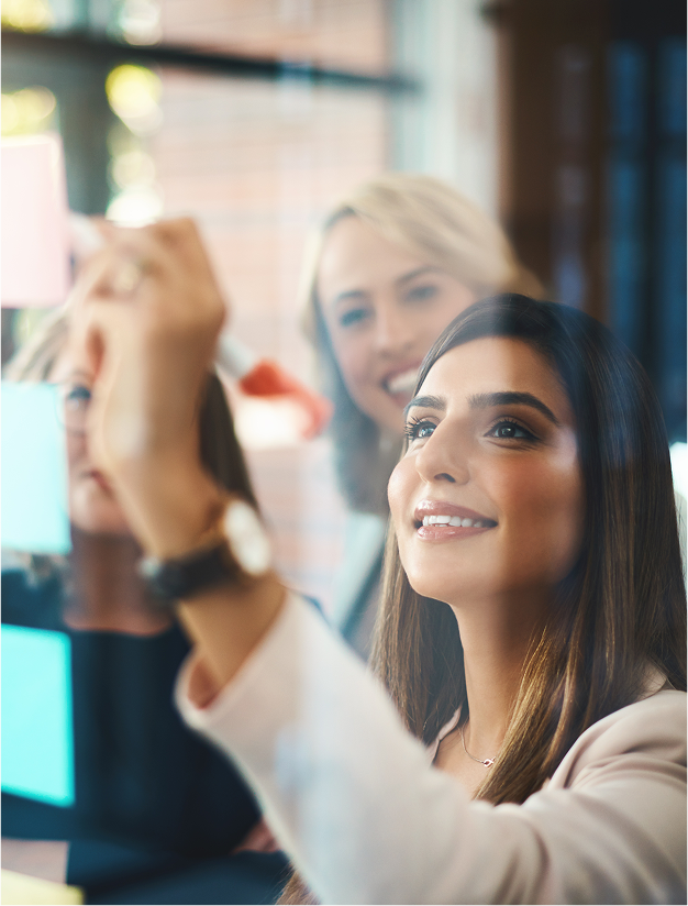 Colleagues collaborating with notes on glass board