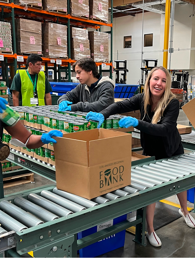 Colleagues handling boxes on conveyor line at a food bank