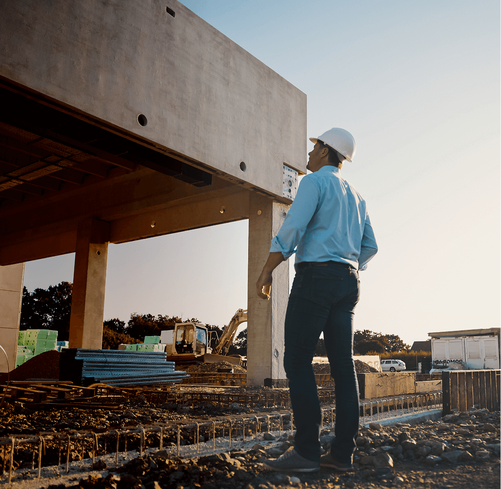 Construction worker in a hard hat looking up at a concrete structure