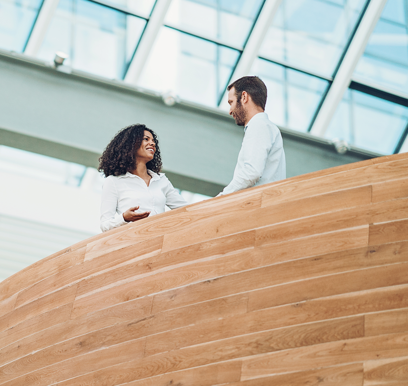 Two professionals talking in office atrium