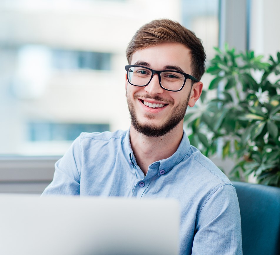 Young professional smiling while working on laptop