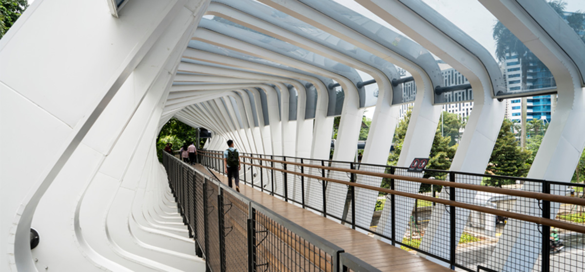 People walking across a bridge in an architecturally interesting tunnel structure