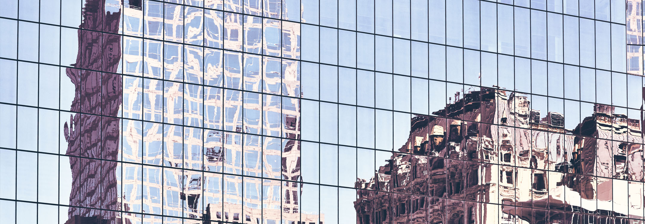 Buildings reflected off a glass building facade, creating a distorted and rippled visual effect.